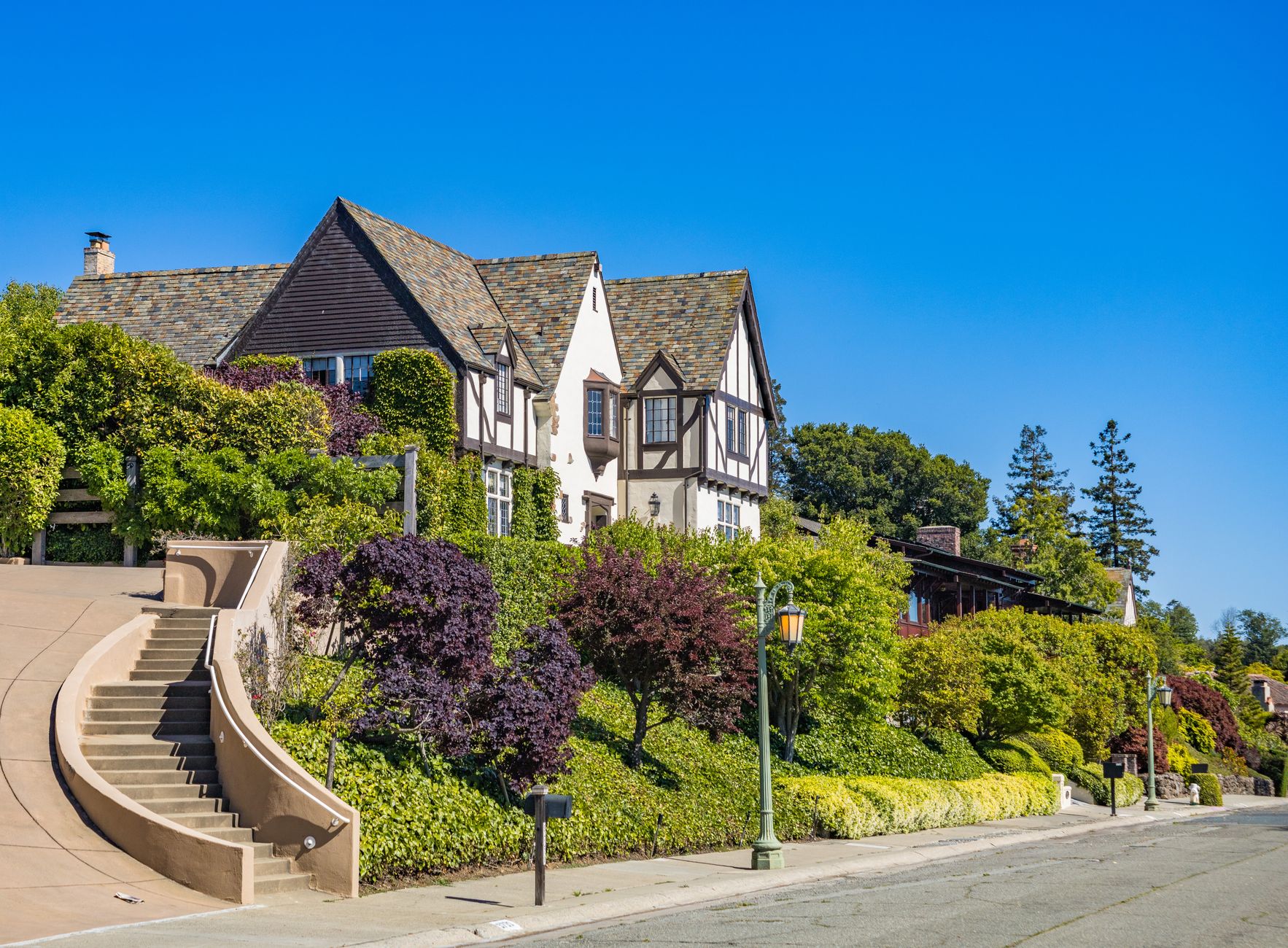 Beautiful Tudor style house with lush greenery on a sunny day, perfect for real estate listings.