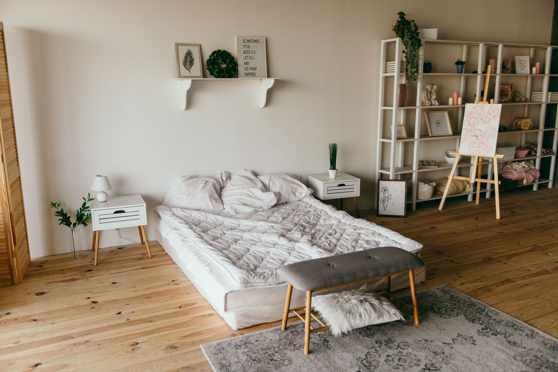 Spacious modern bedroom with minimalist decor, featuring a low bed, wooden floors, and shelf storage.