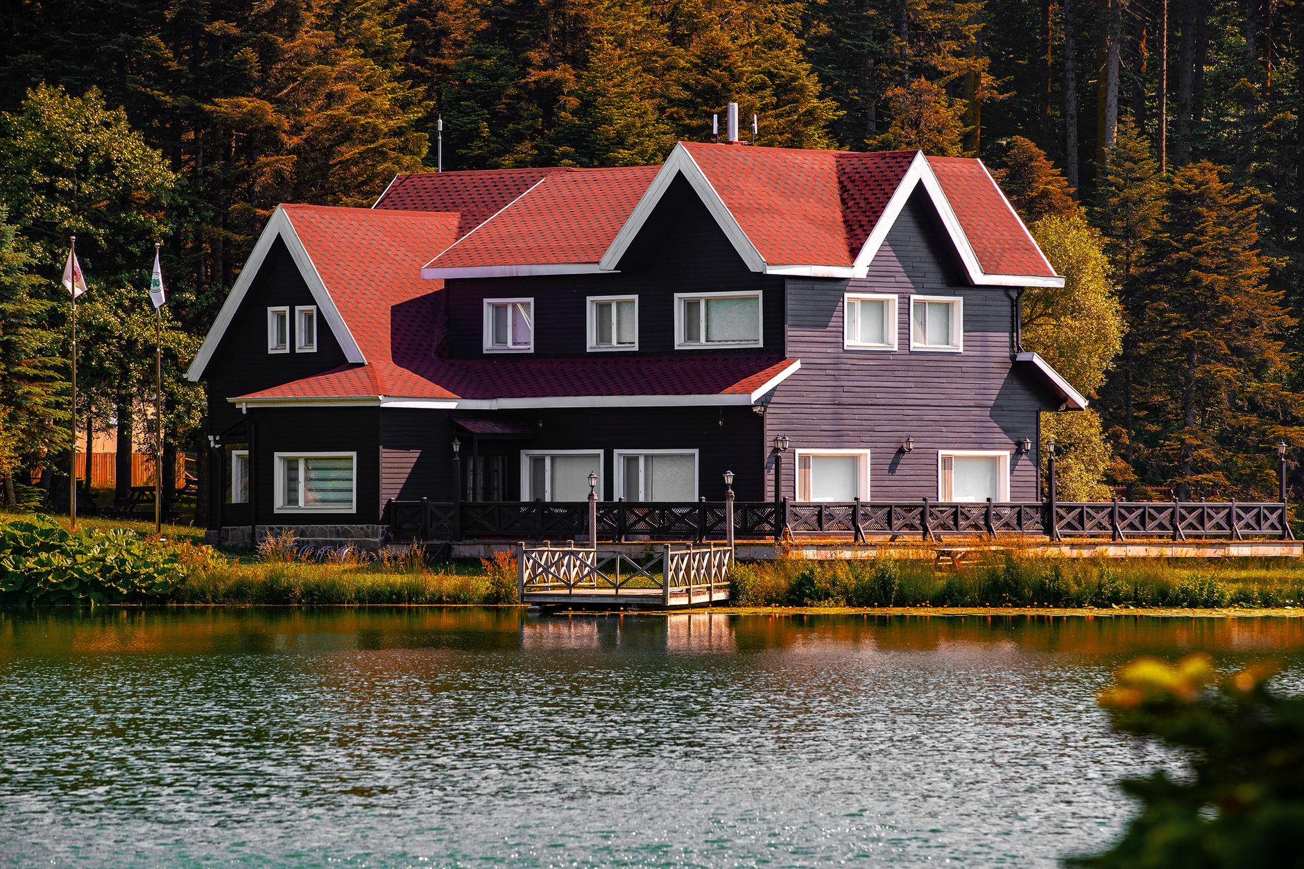 Picturesque lakeside house surrounded by lush forest and serene waters.
