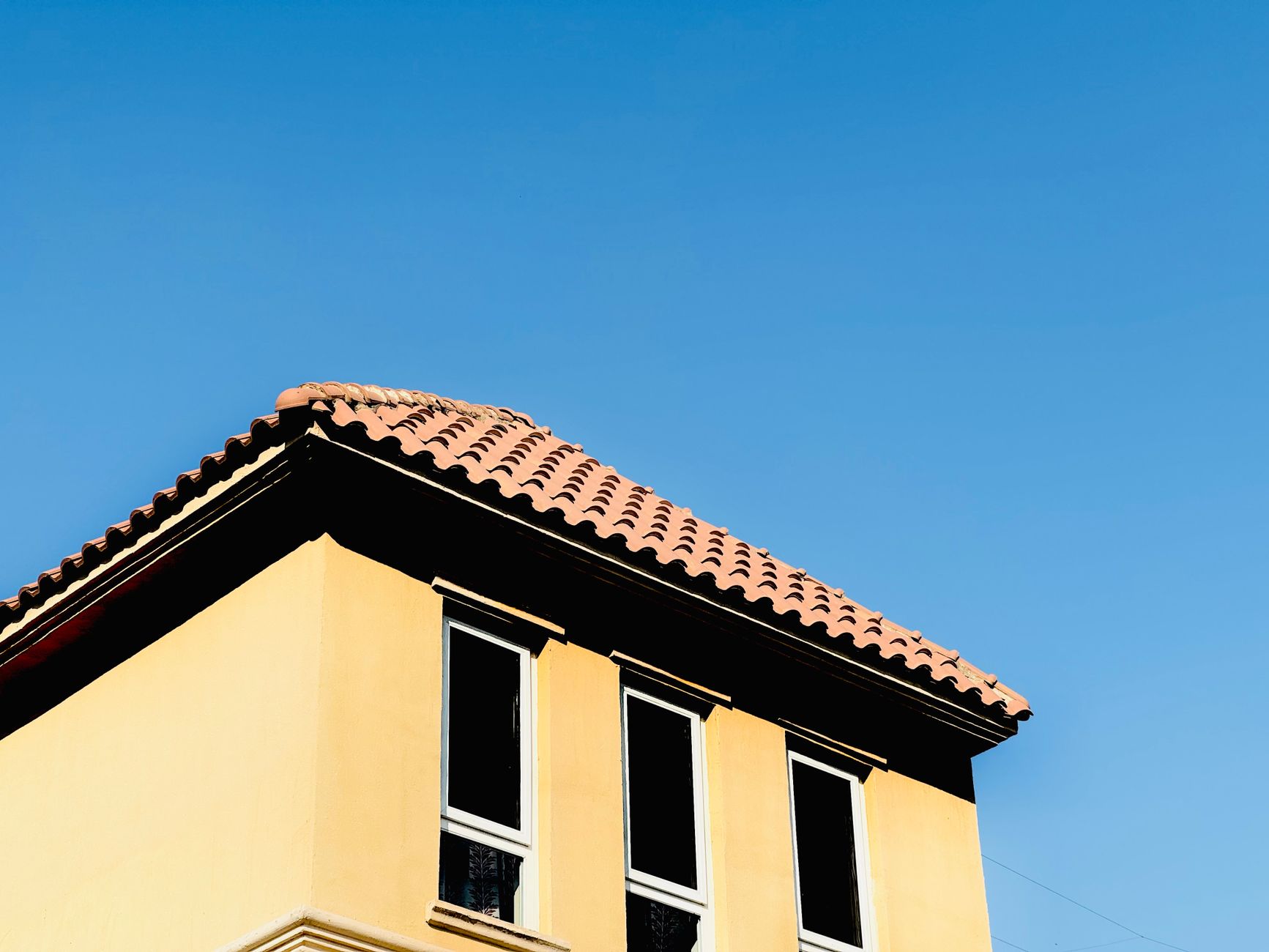 A Mediterranean style building rooftop with terracotta tiles under a clear blue sky.
