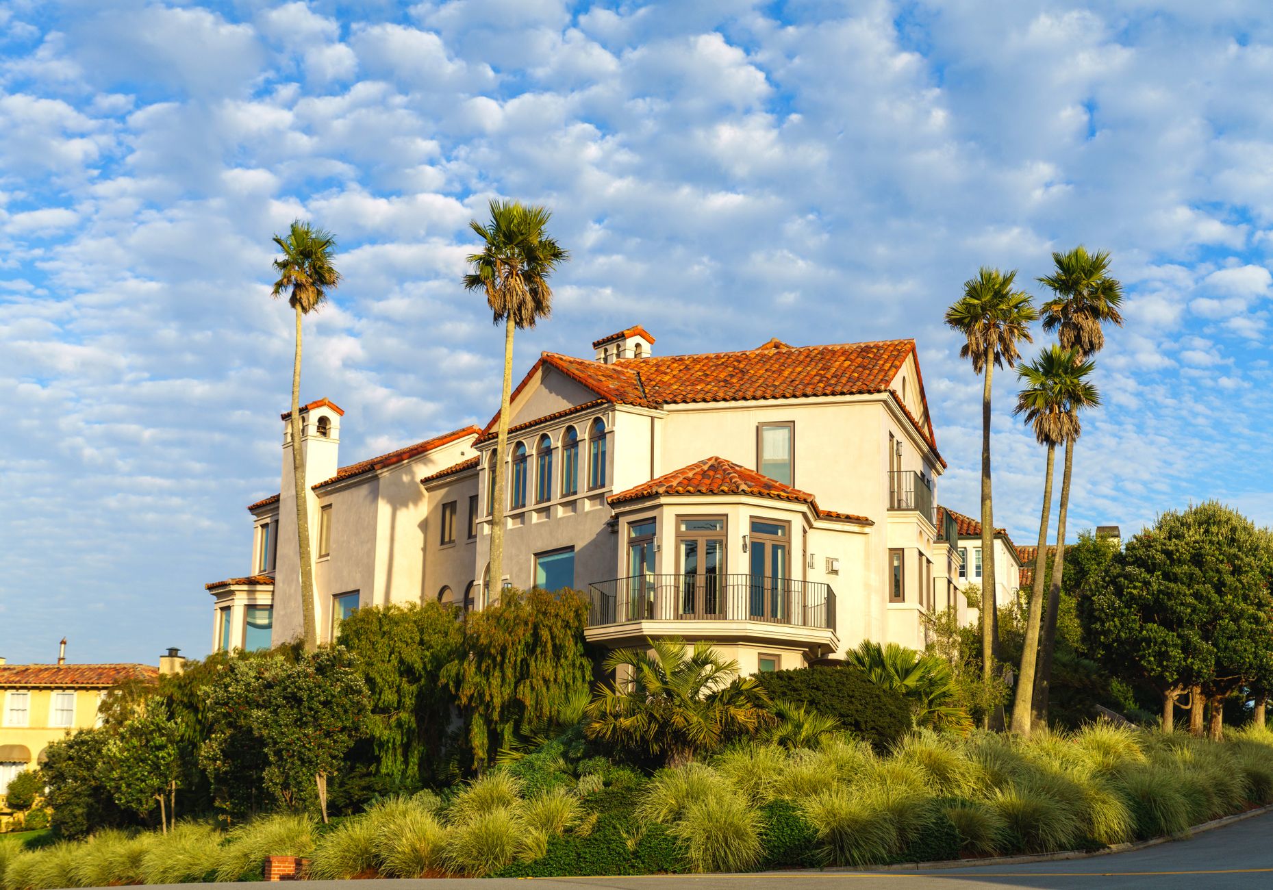 Elegant Mediterranean villa surrounded by palm trees under a bright blue sky.
