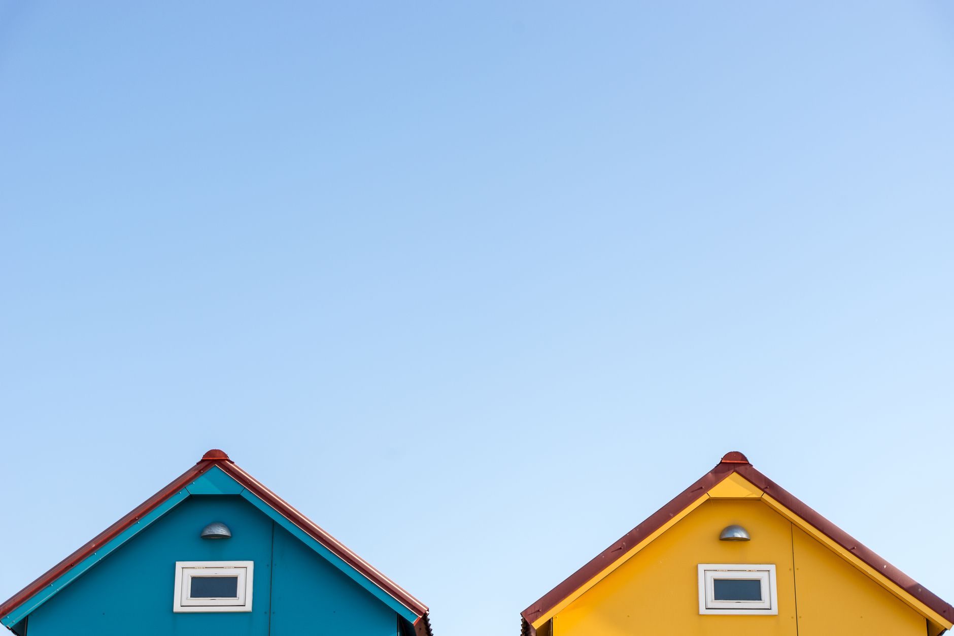 Vibrant blue and yellow house tops with clear sky background, ample copyspace for text.