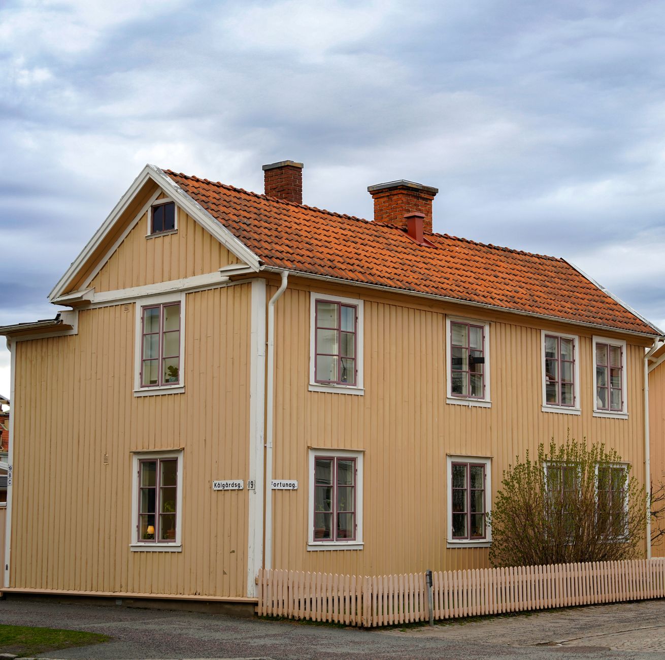 Charming wooden house with red roof in a Scandinavian village under an overcast sky.