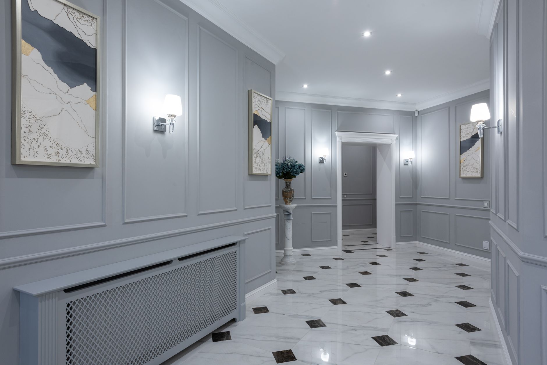 Interior of corridor of contemporary villa with shiny tiled floor and gray walls decorated with paintings and lamps