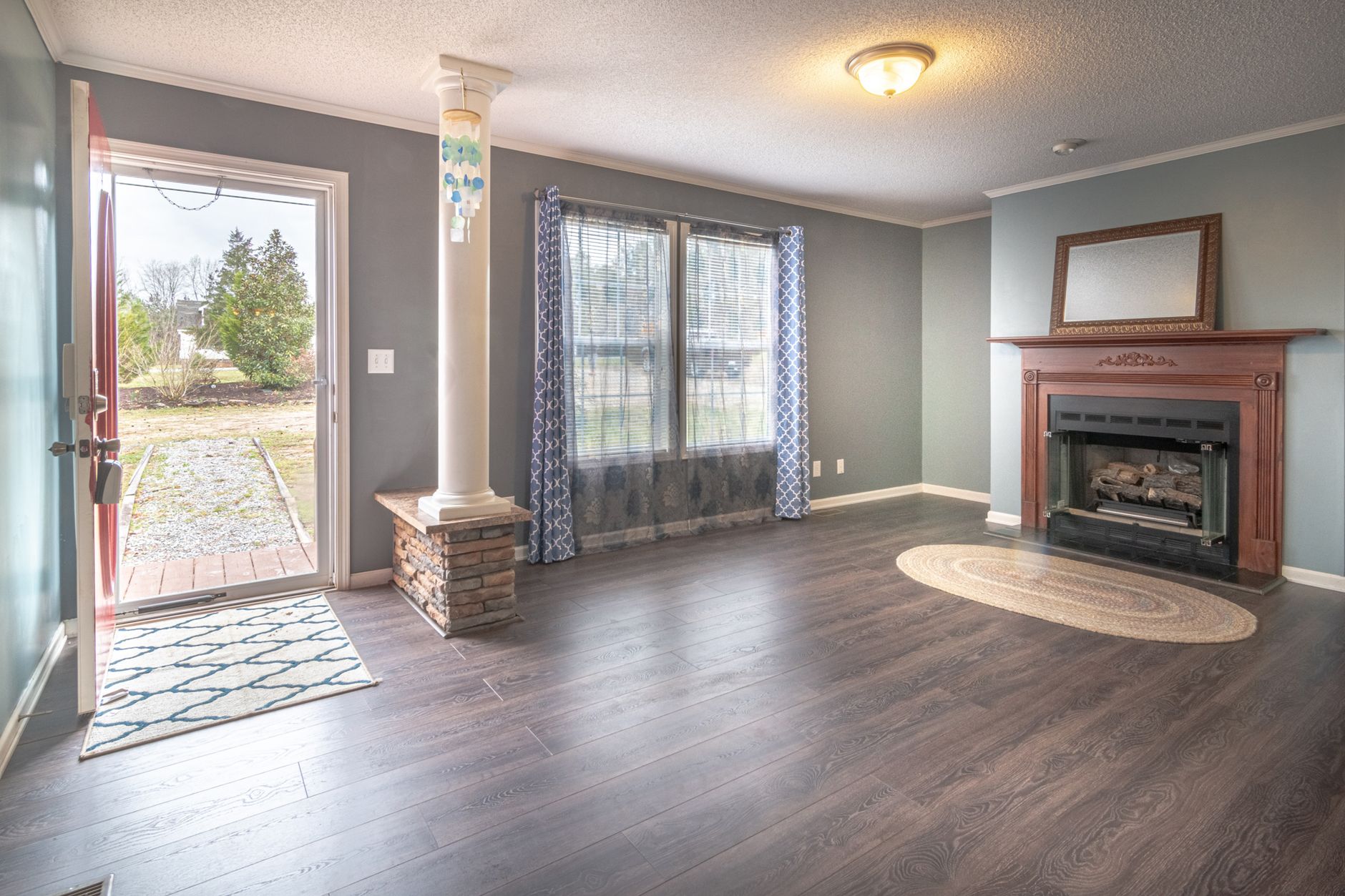 Inviting living room with fireplace, large windows, and open door leading outside.