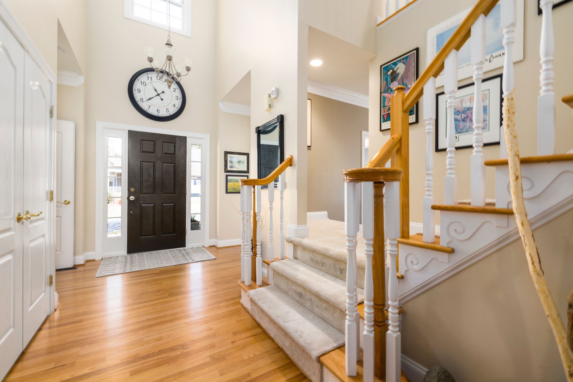 A bright and spacious modern entrance hall featuring a large clock and elegant staircase.