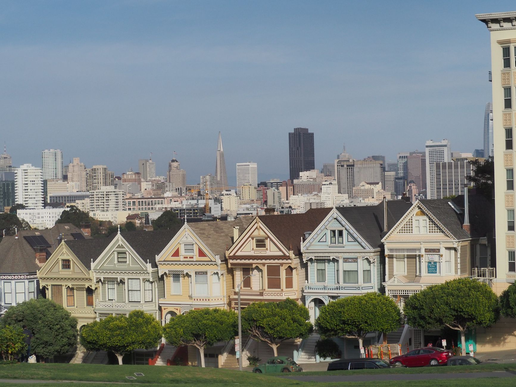 The famous Painted Ladies with San Francisco's skyline as backdrop, showcasing Victorian architecture.
