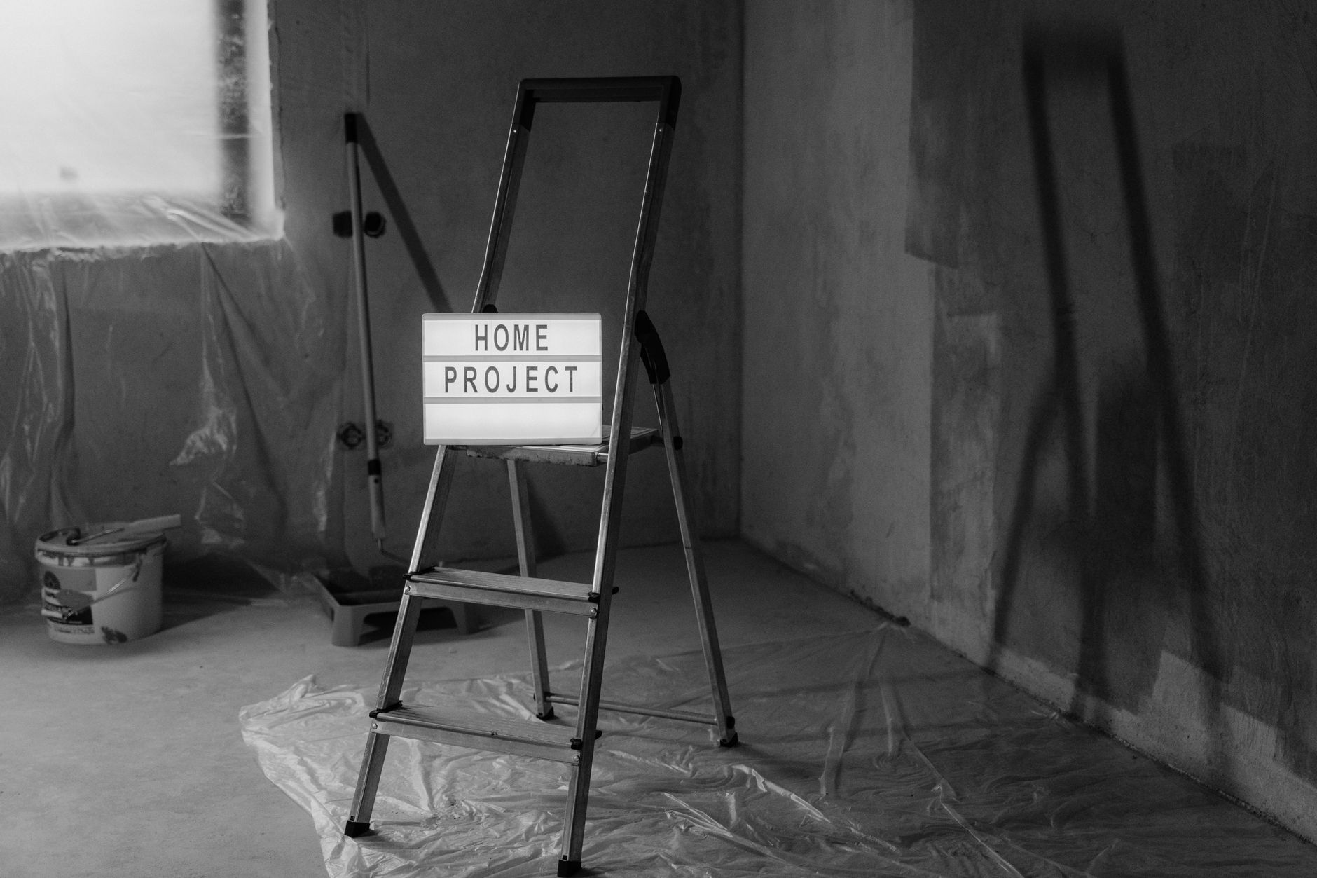 Black and white image of a step ladder with a 'home project' sign in a renovation setting.