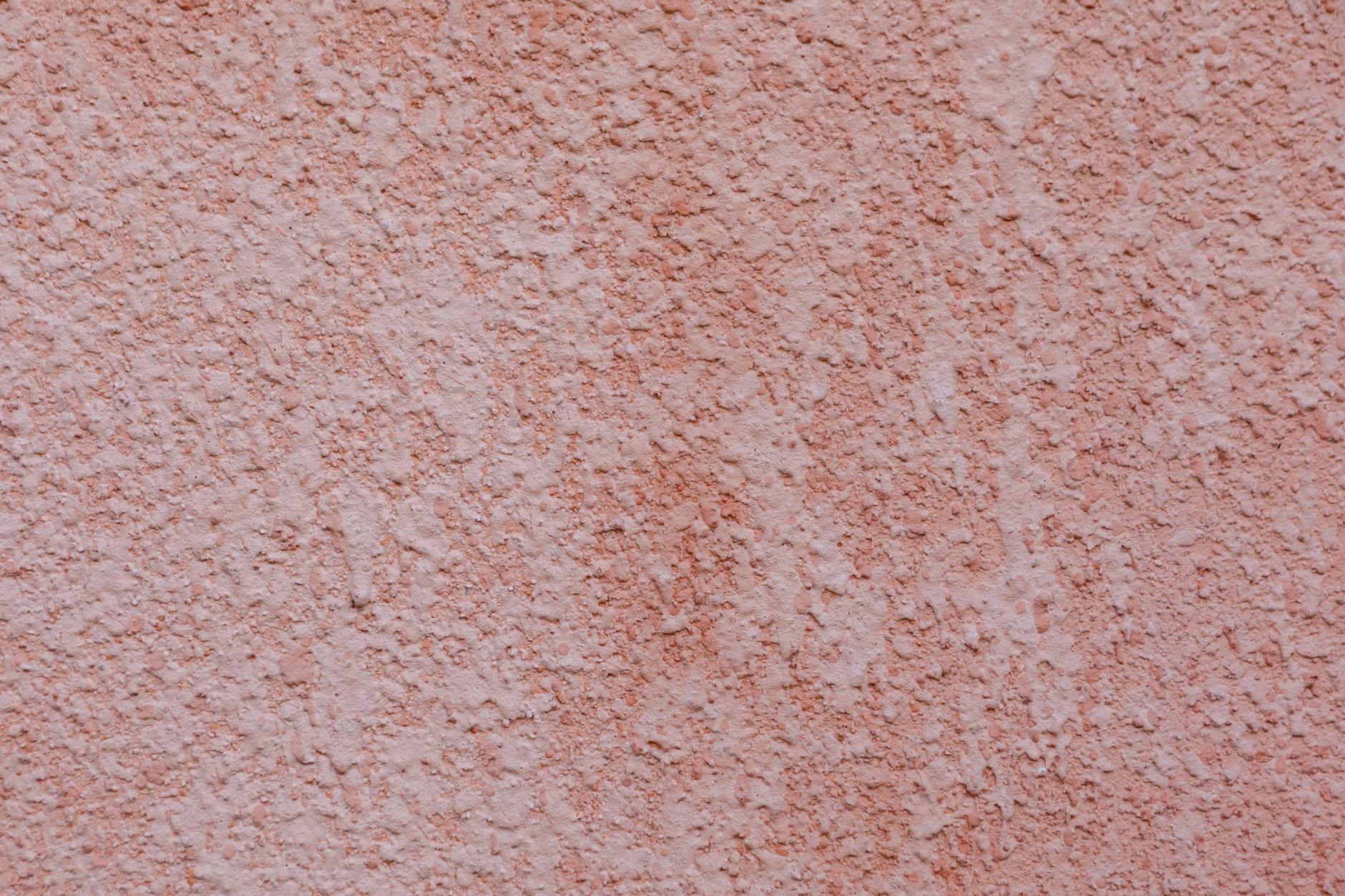 Textured background of wall painted in coral light and covered with embossed plaster