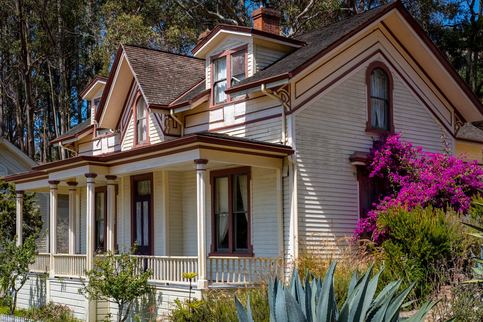 Beautiful Victorian house surrounded by vibrant gardens and trees, perfect for architecture and nature lovers.