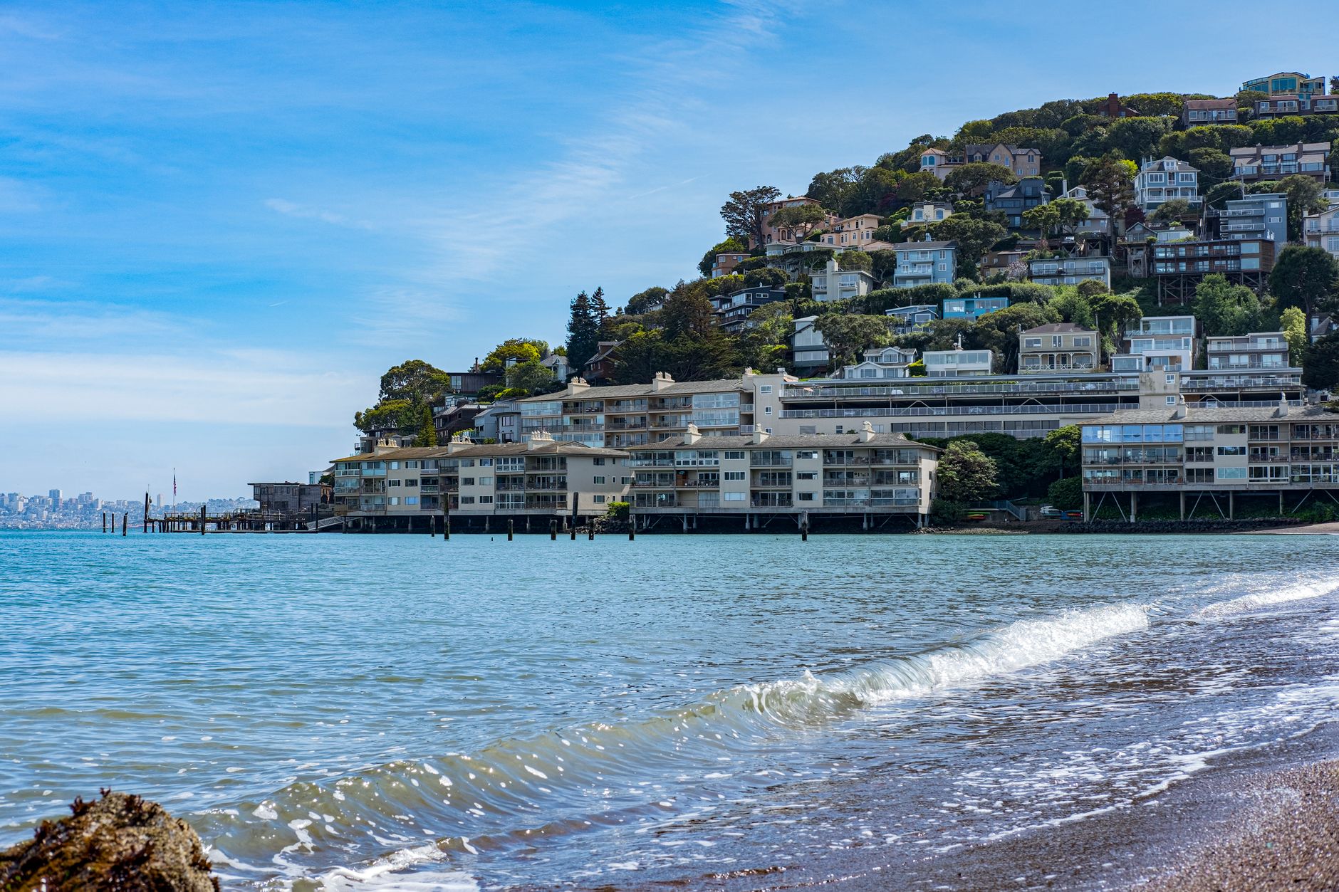 Picturesque coastal town with hillside homes and beachfront along a tranquil bay.