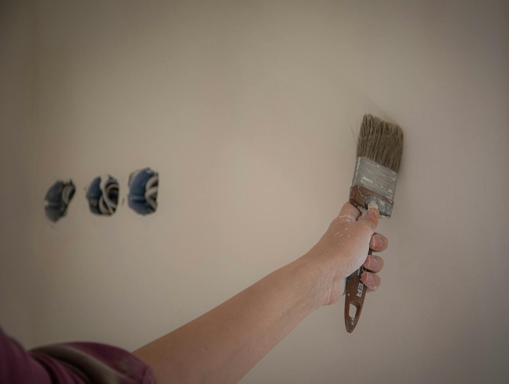 Professional painter sanding a wall surface during preparation for painting an HOA building