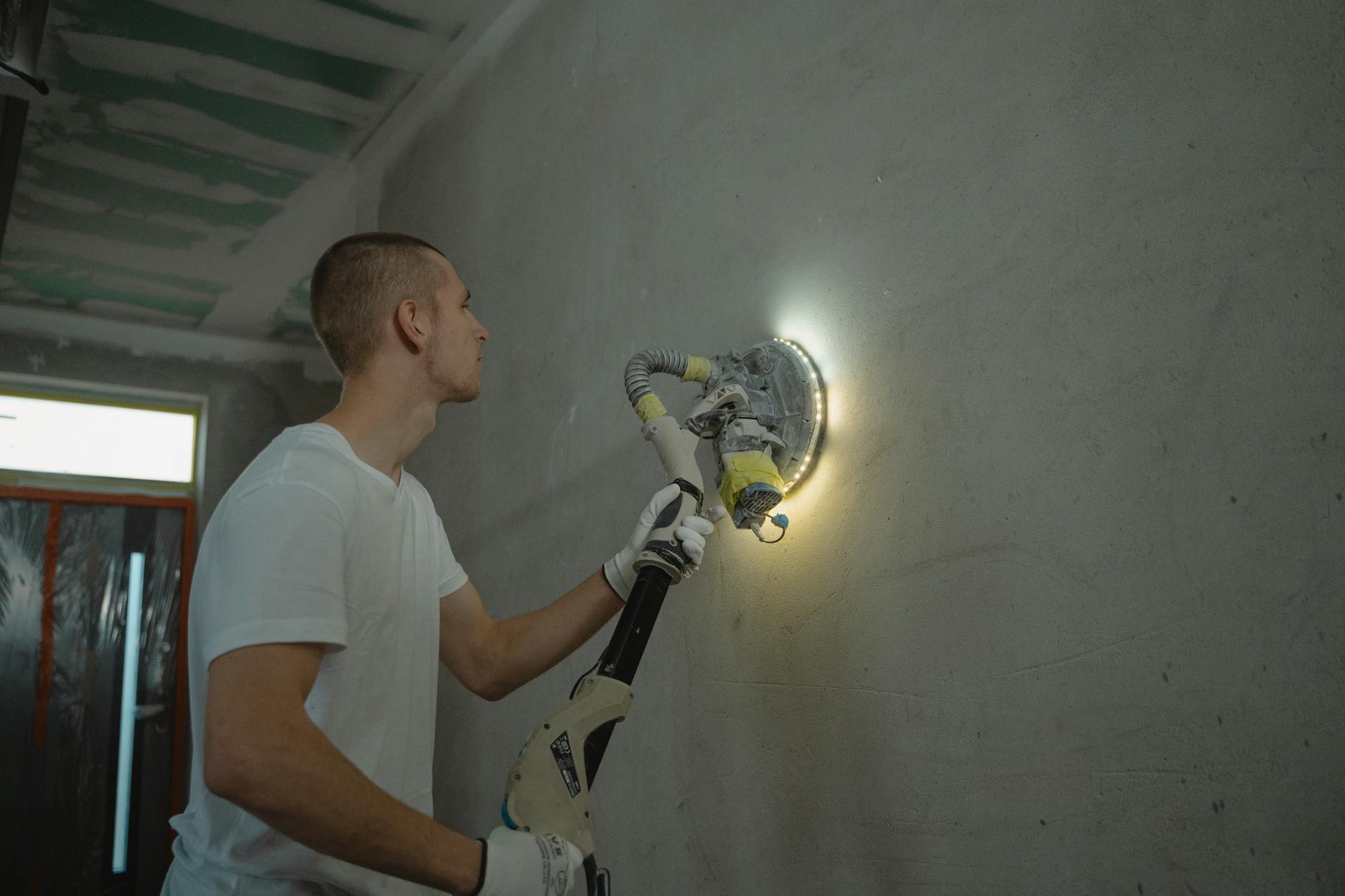 Professional painter preparing a wall in a Bay Area home with scraping and sanding tools