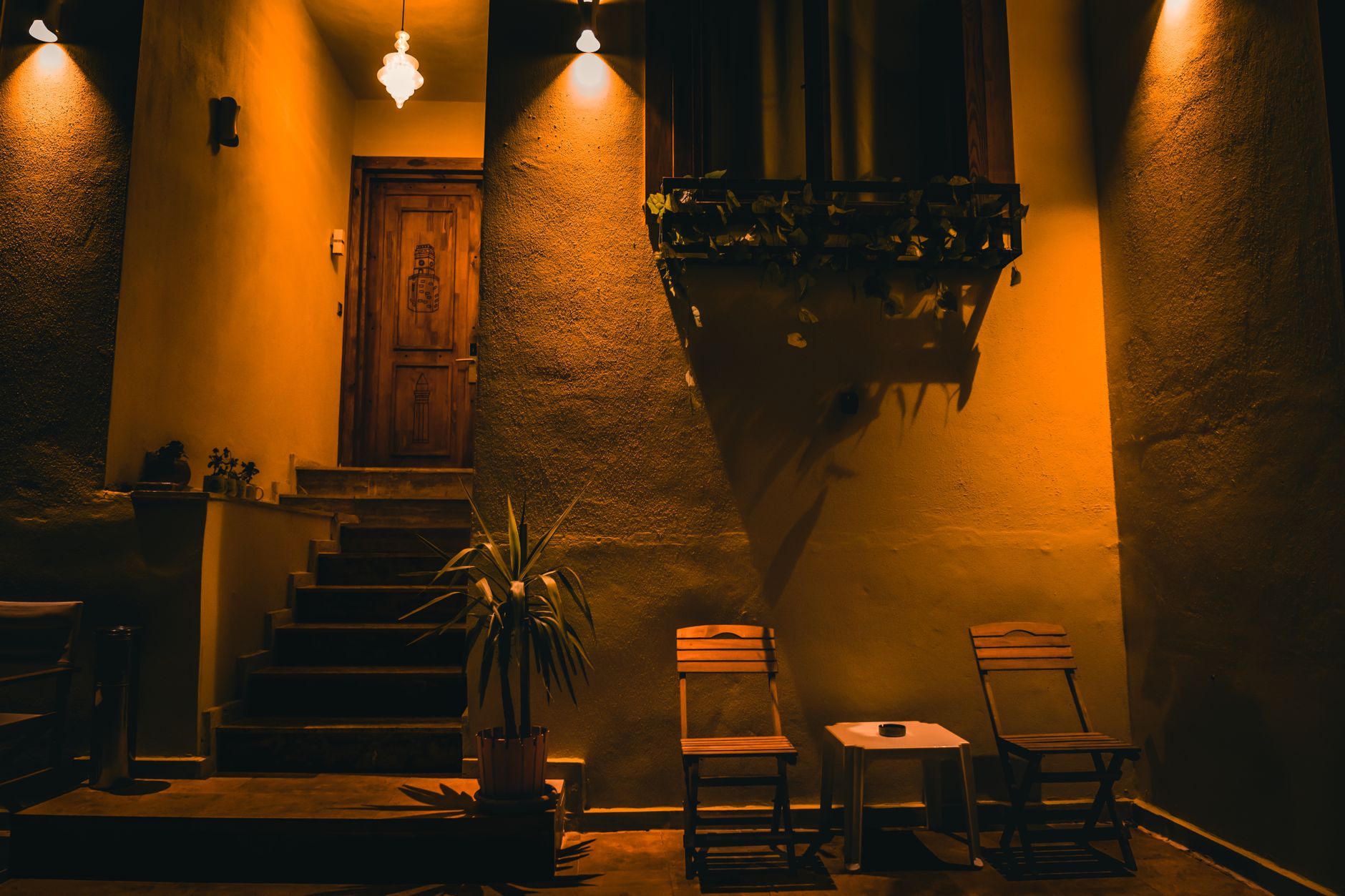 Warmly lit patio with chairs under dramatic lighting, creating a cozy atmosphere.