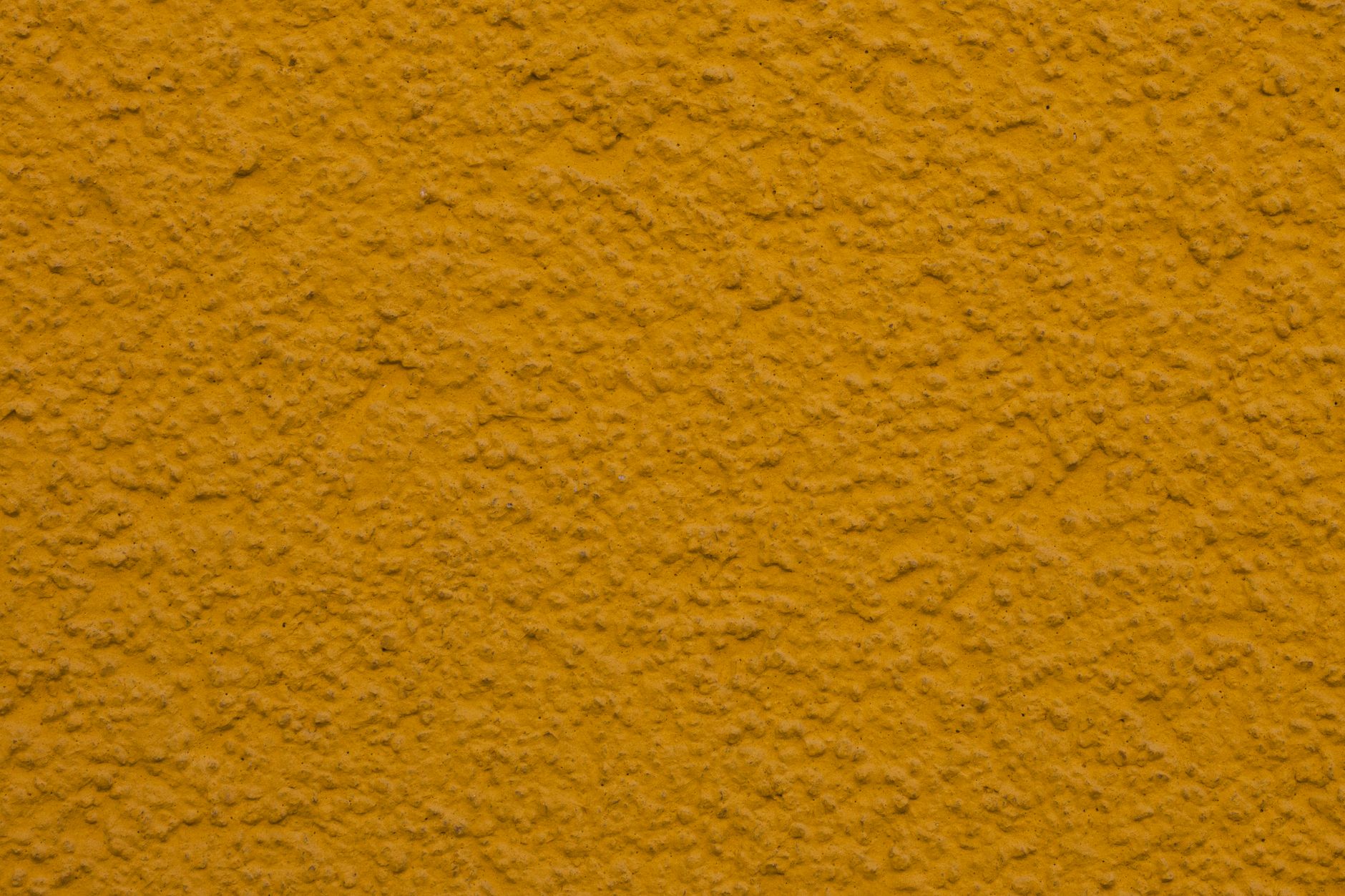 Close-up of a textured yellow plaster wall, ideal for backgrounds or design projects.